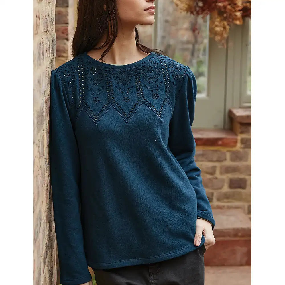 Woman wearing a blue sweater with intricate detailing in an outdoor setting