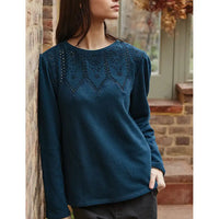 Woman wearing a blue sweater with intricate detailing in an outdoor setting