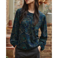 Woman wearing a dark blue floral patterned blouse with a blurred background