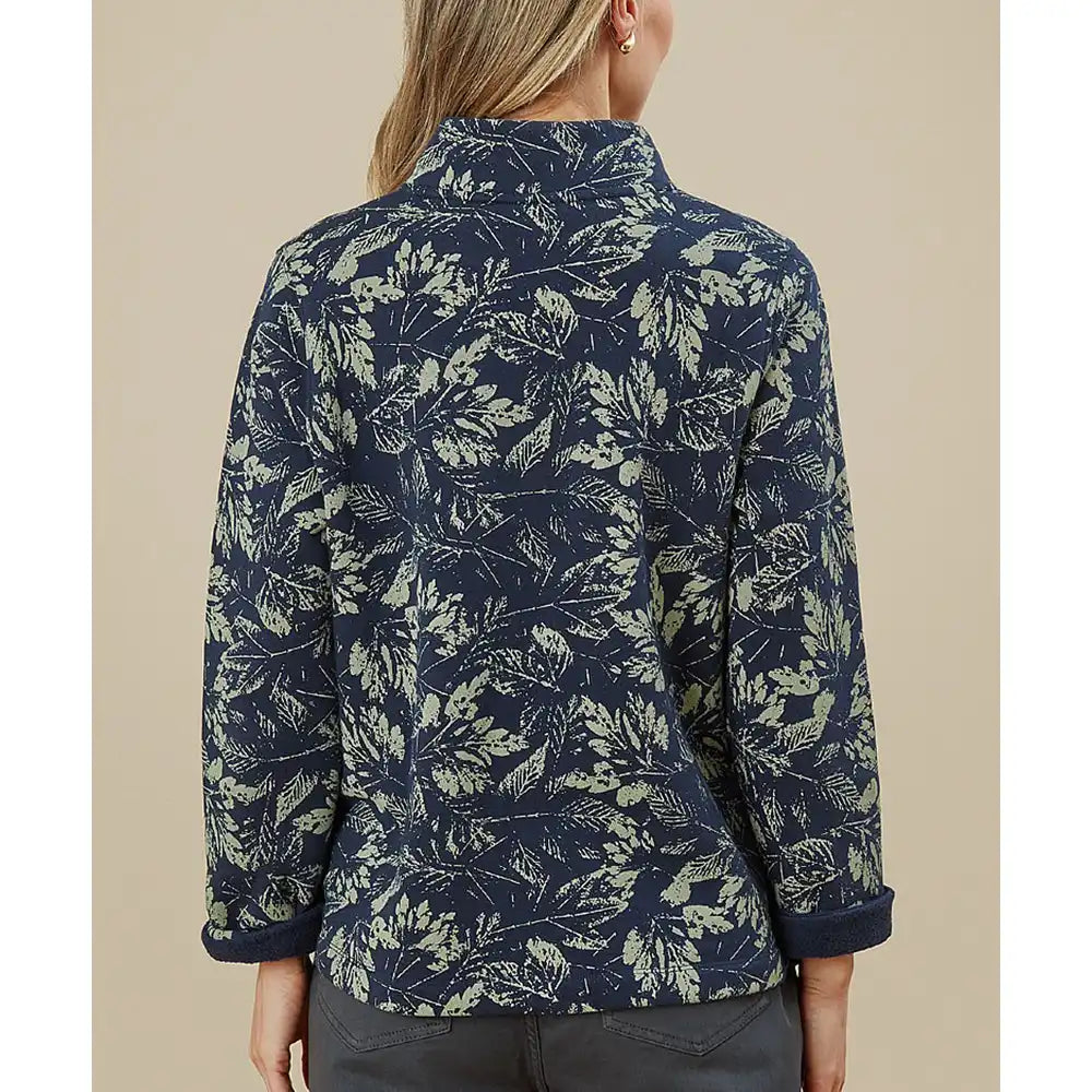 Person wearing a navy blue floral patterned shirt against a beige background