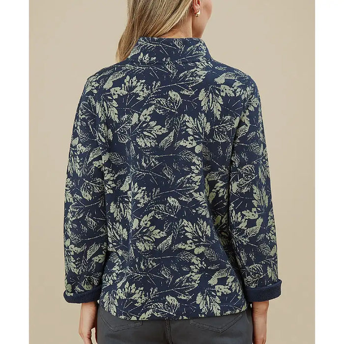 Person wearing a navy blue floral patterned shirt against a beige background