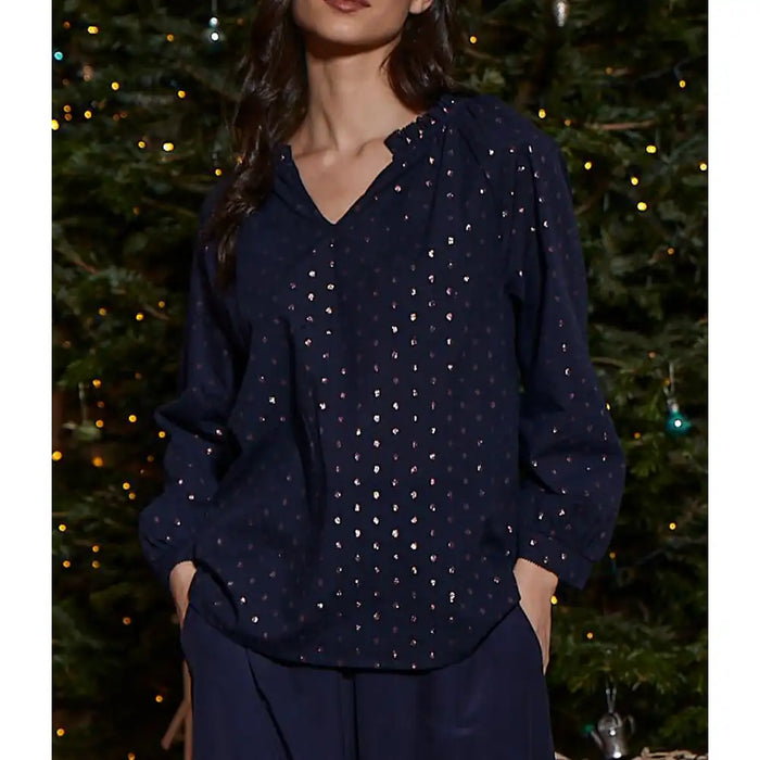 Person wearing a navy blue blouse with small patterns against a festive background