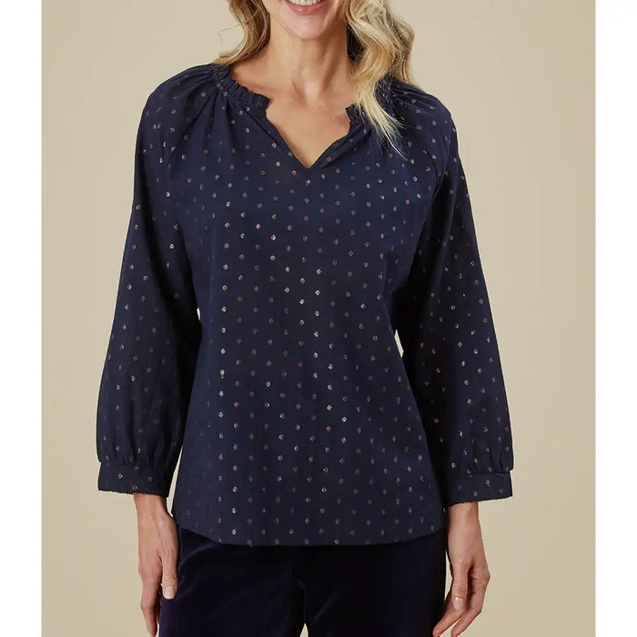 Woman wearing a navy blue blouse with a subtle pattern on a beige background