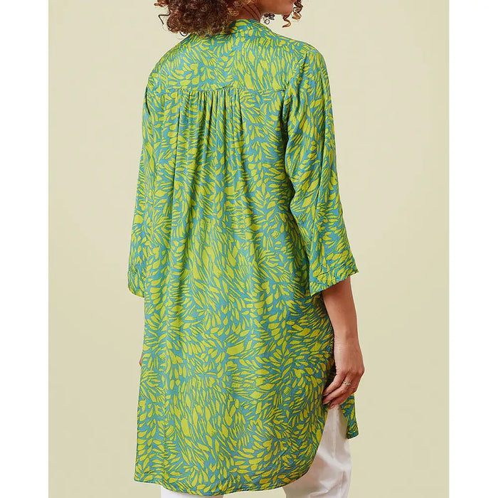 Green and yellow patterned dress worn by a person on a beige background