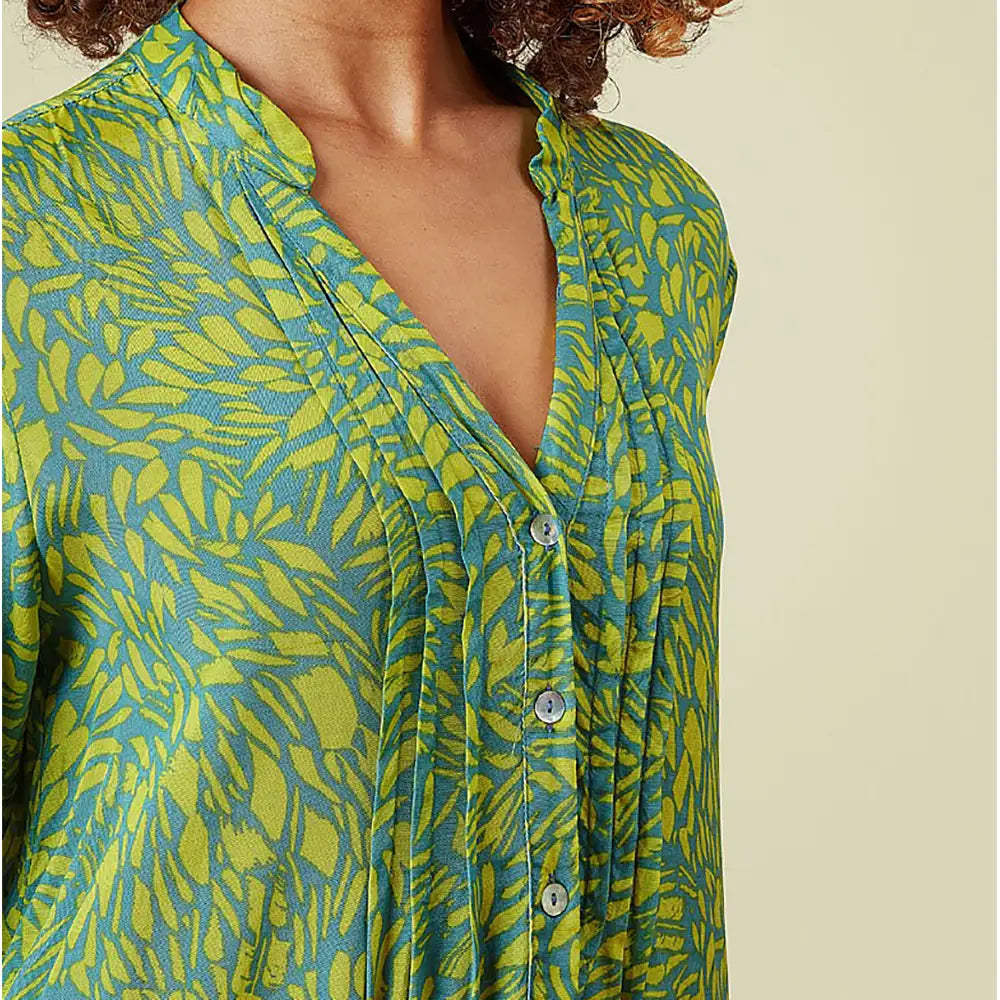 Green and blue patterned shirt worn by a person on a beige background