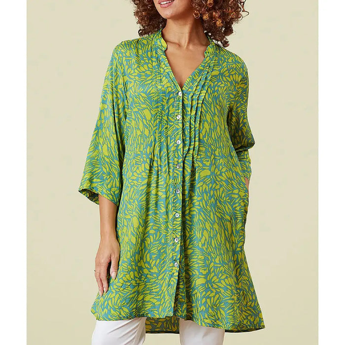 Green and yellow patterned dress worn by a person on a beige background