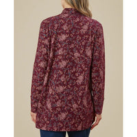 Maroon floral patterned shirt worn by a person on a beige background