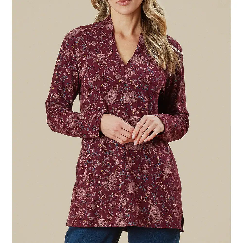 Woman wearing a burgundy floral long-sleeve top against a beige background