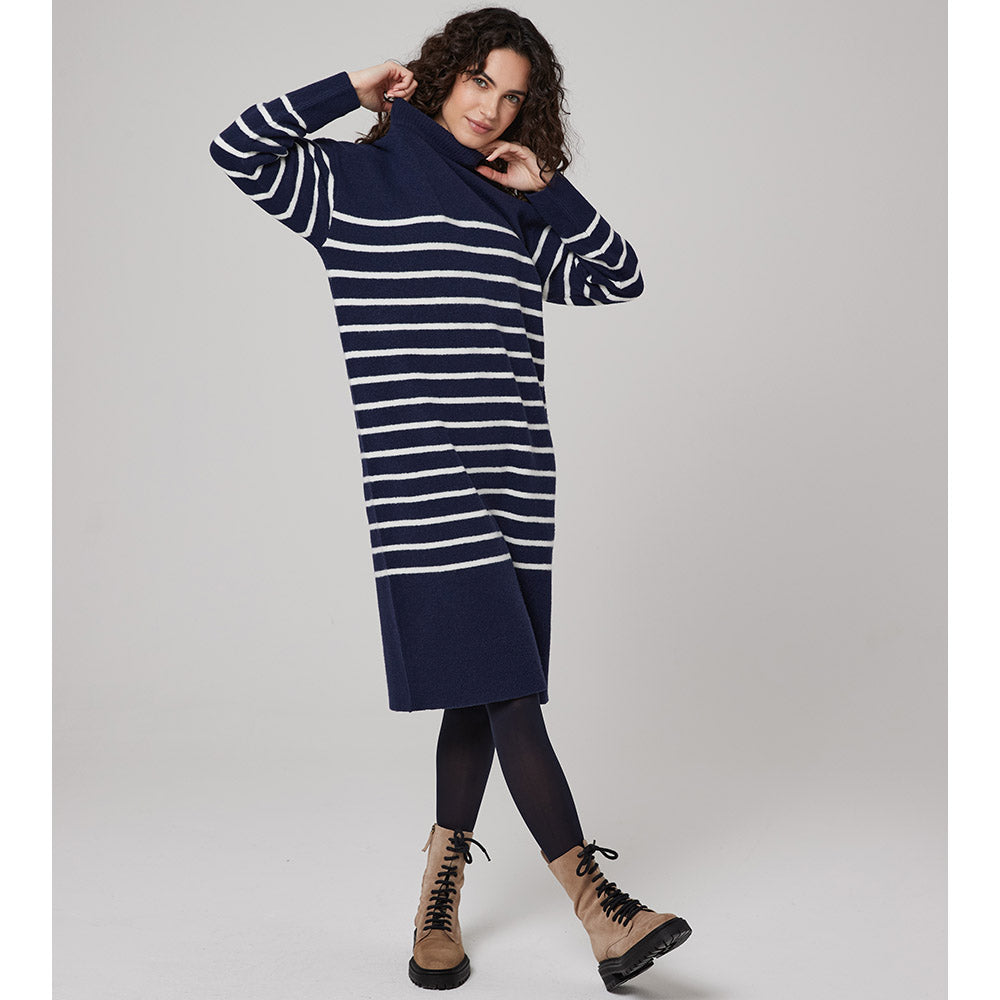 Navy and white striped dress that falls to the knee of black tight clad legs wearing beige lace up combat boots. Long sleeves and a cowl neckline. 