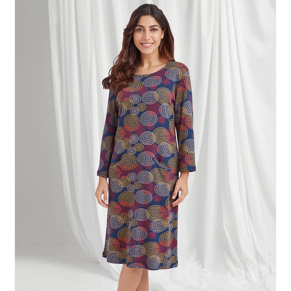 th front of a royal blue dress with long sleeves and knee length with a mandala style overlapping circular print in reds, white and yellow.