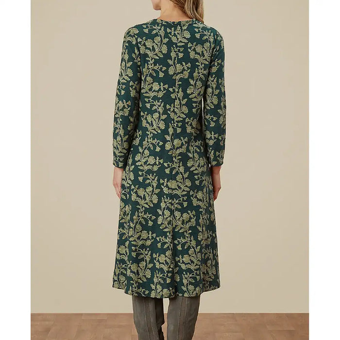 Green floral dress worn by a person on a beige background