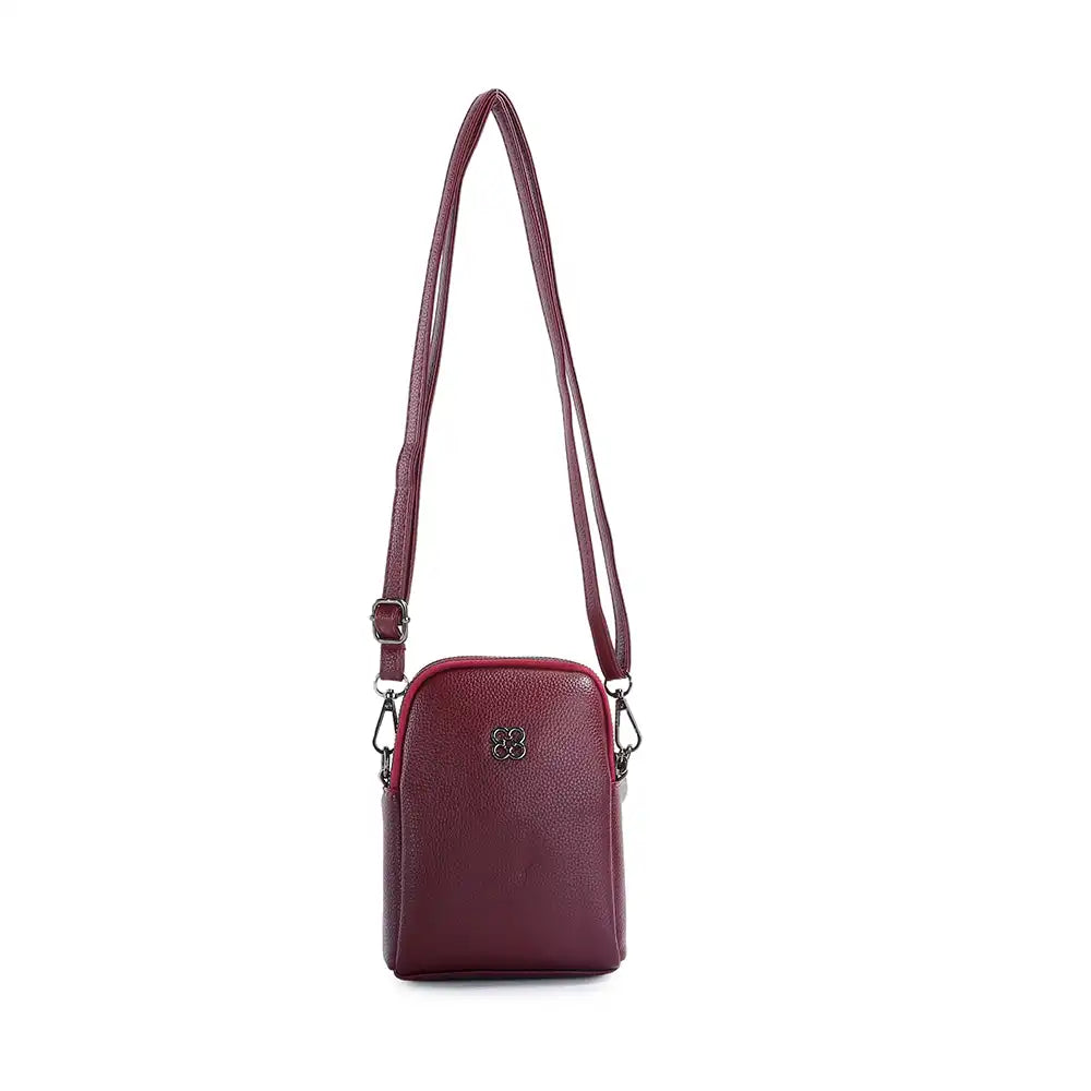 A small burgundy pebbled leather crossbody bag with a long matching shoulder strap and a small silver-tone logo emblem on the front, shown against a plain white background.