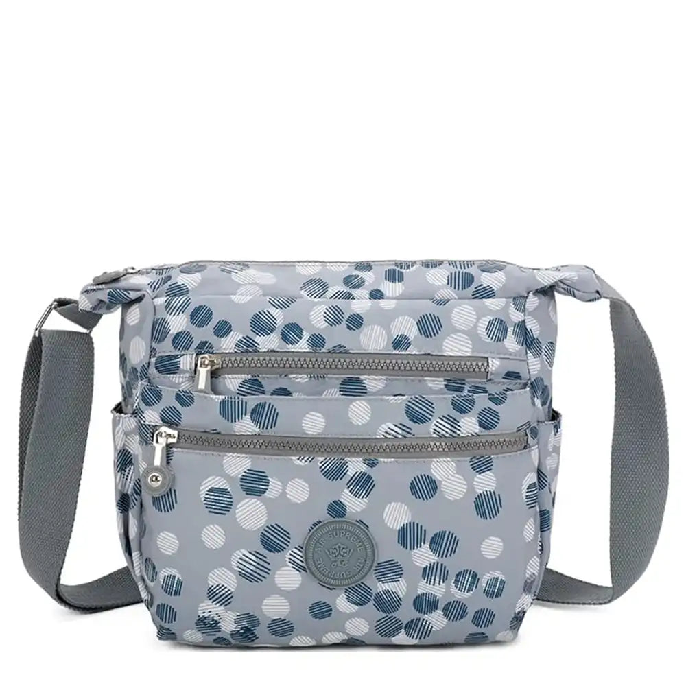 Landscape messenger shoulder bag. Grey with white and blue dots. Grey fabric strap. Zip pockets.