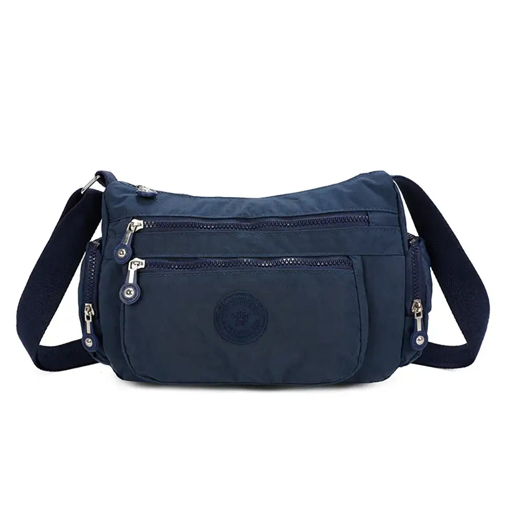 Navy blue shoulder bag with multiple zippers on a white background