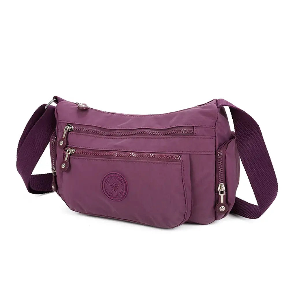 Purple shoulder bag with multiple zippers on a white background