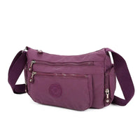 Purple shoulder bag with multiple zippers on a white background