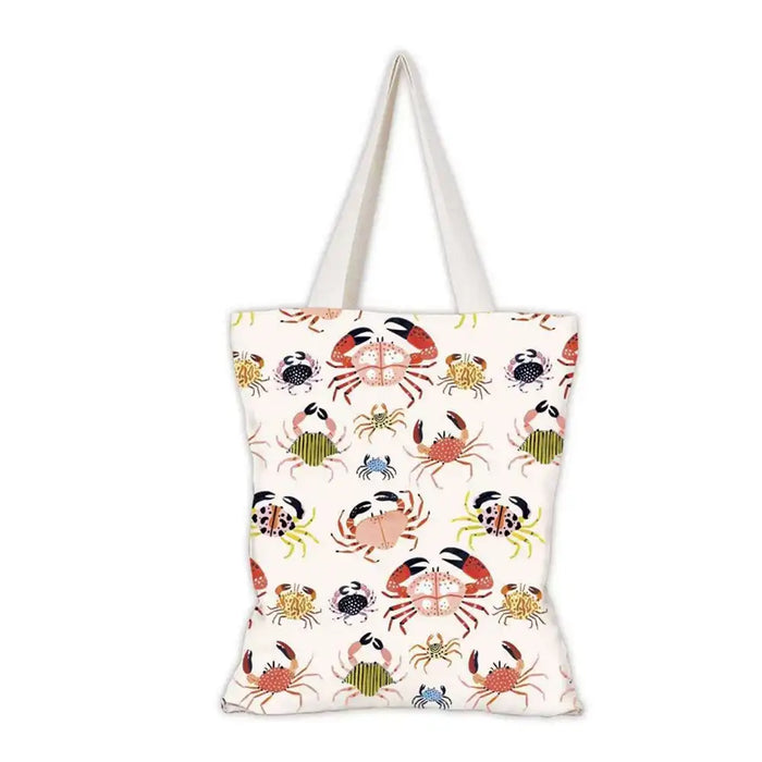 A white canvas tote bag with a repeating pattern of colorful crabs in red, orange, green, blue, and black, featuring two white shoulder straps.