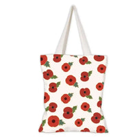 A canvas tote bag with a repeating pattern of red poppies with green leaves on an off-white background, featuring two cream-colored shoulder straps.