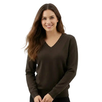 A woman with long brown hair wearing a dark brown V-neck knit sweater, standing against a plain white studio background.