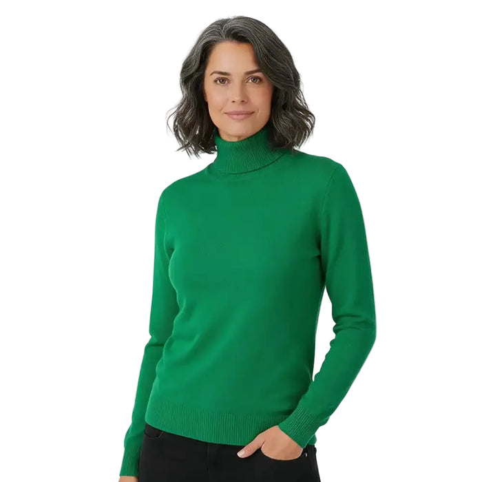 A woman wearing a bright green ribbed turtleneck sweater, paired with black pants, standing against a plain white studio background.