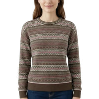 A woman wearing a long-sleeve crewneck sweater with a brown, pink, and cream Fair Isle pattern, paired with blue jeans against a plain white background.
