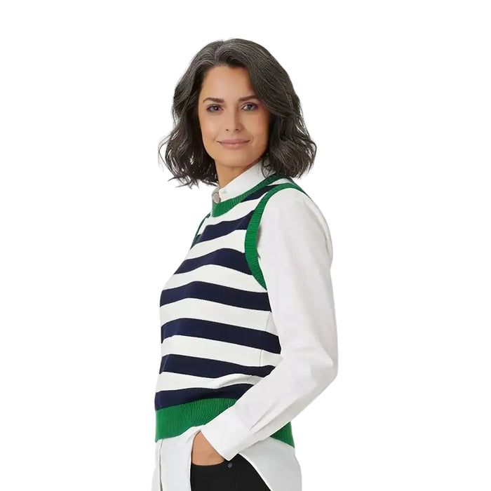 A woman wearing a white long-sleeve collared shirt under a navy and white horizontally striped knit sweater vest with green trim, photographed against a plain white studio background.