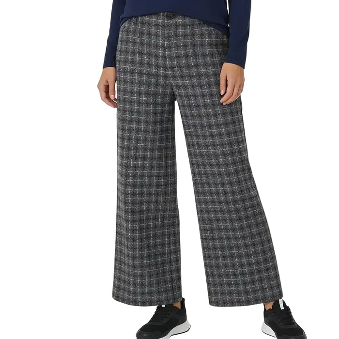 A person wearing wide-leg plaid trousers in gray and black, paired with a navy long-sleeve top and black sneakers, shown against a plain white studio background.