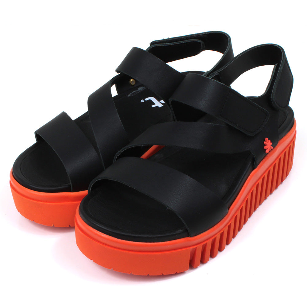 Art black sandals. Black footbed and bright orange ridged orange soles. Angled view.
