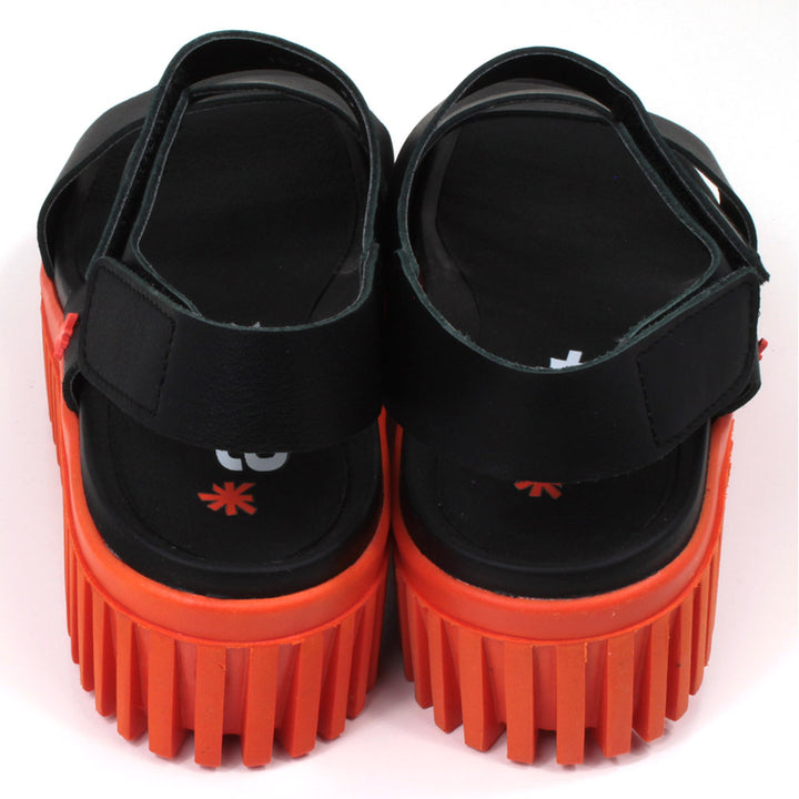 Art black sandals. Black footbed and bright orange ridged orange soles. Back view.