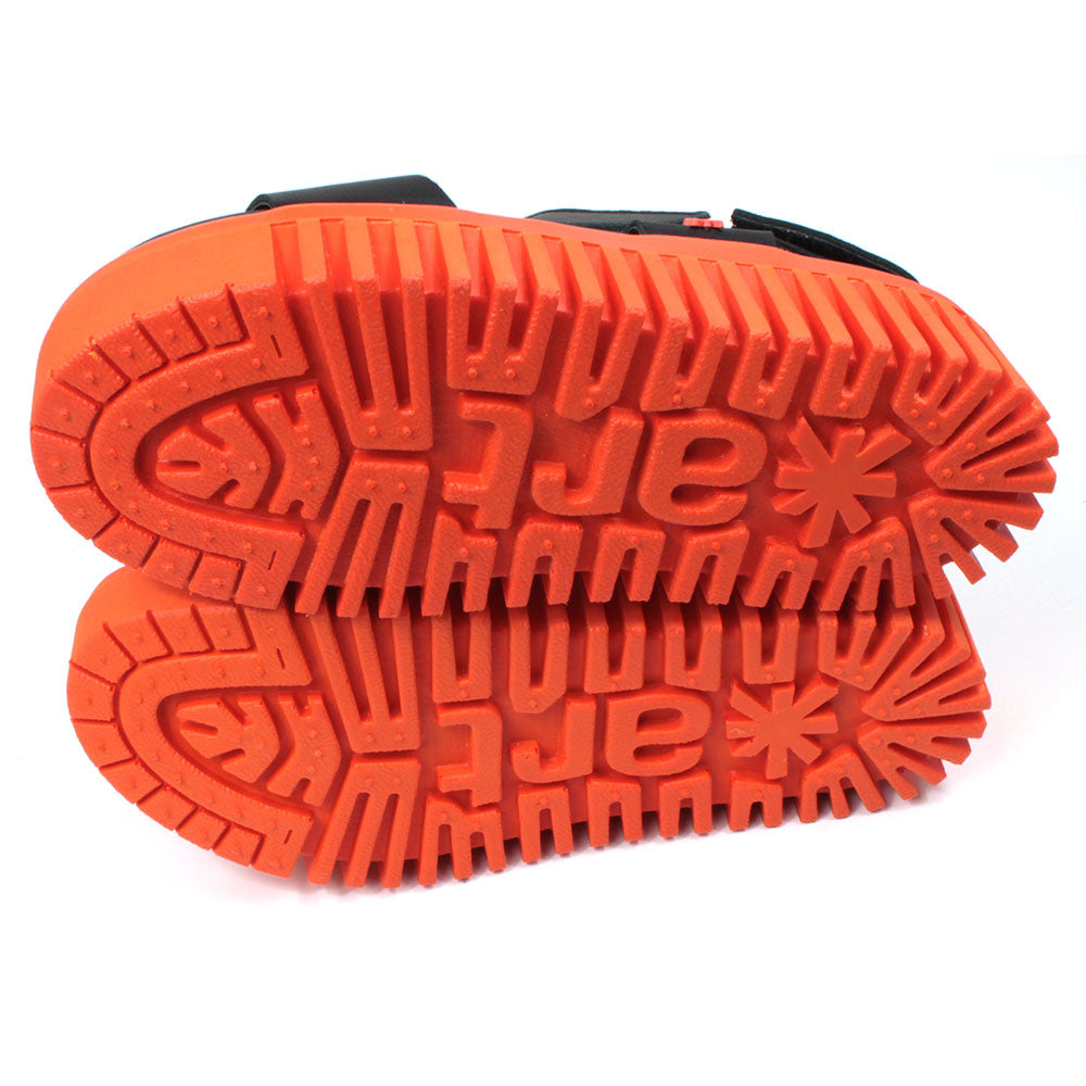 Art black sandals. Black footbed and bright orange ridged orange soles. View of soles.