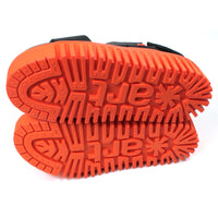 Art black sandals. Black footbed and bright orange ridged orange soles. View of soles.