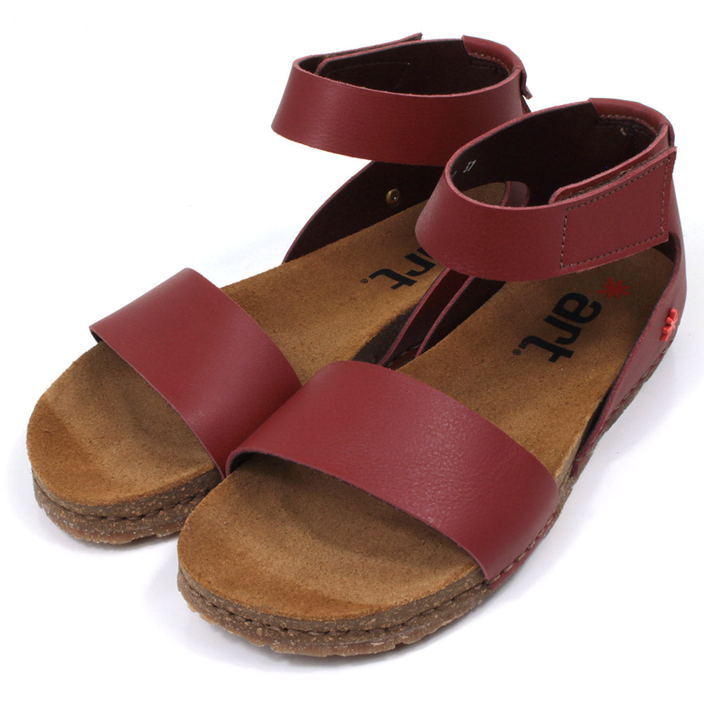 Art red tan sandals with single wide footstrap and Velcro fitting around the ankle. Tan coloured footbeds. Angled view