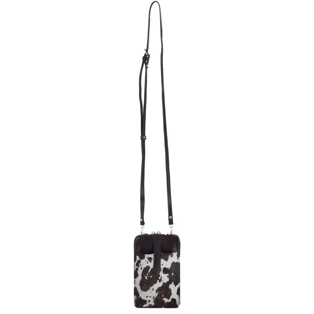A small crossbody phone bag with a black and white cow print body and a solid black strap, shown against a plain white background.