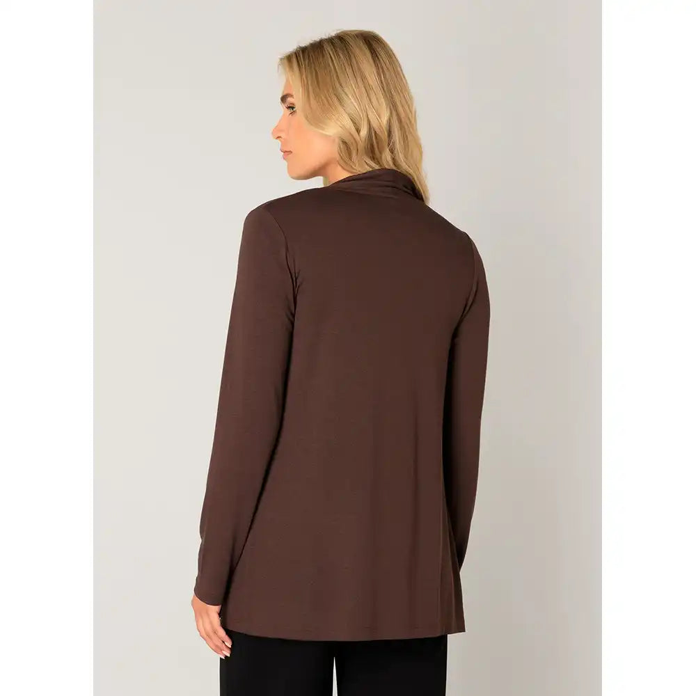 A woman with blonde hair is shown from the back wearing a solid dark brown long-sleeve top, paired with black pants, against a light gray studio background.