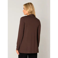 A woman with blonde hair is shown from the back wearing a solid dark brown long-sleeve top, paired with black pants, against a light gray studio background.