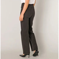 A person shown from the waist down wearing dark charcoal gray wide-leg jeans, a white top, and black pointed-toe heels against a plain light gray studio background.