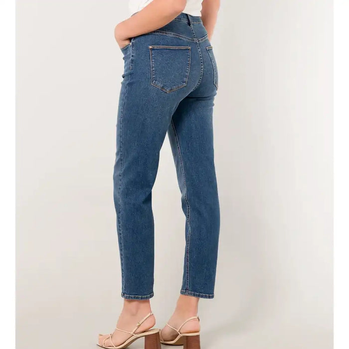 Person wearing blue jeans on a plain background