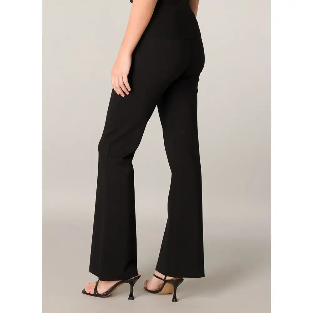 A model shown from the back wearing black high-waisted flared pants and black strappy high-heeled sandals against a light gray studio background.