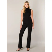A woman modeling wide-leg blacj pants, paired with black strappy high-heeled sandals, against a neutral light gray studio background.