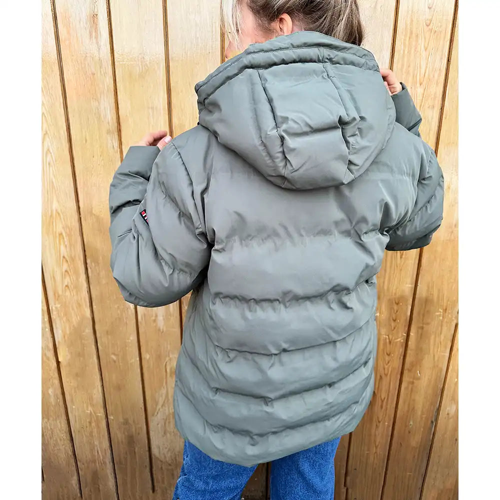 Person wearing a gray puffer coat standing against a wooden fence