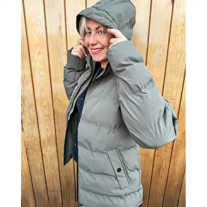Person wearing a gray puffer coat against a wooden background