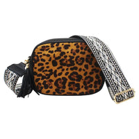 A leopard print crossbody bag with a wide, patterned black and white woven strap and gold-tone hardware, shown on a plain white background.
