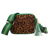 A leopard print crossbody bag with a green and lime green woven strap, gold-tone hardware, and a green and white tassel charm, shown against a plain white background.