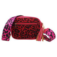 A red and black leopard print crossbody bag with a bright pink and black leopard print strap, gold-tone hardware, and a pink tassel, shown on a plain white background.