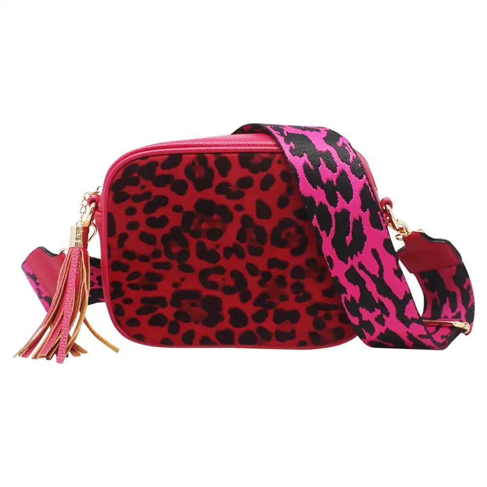 A red and black leopard print crossbody bag with a bright pink and black patterned strap, gold-tone hardware, and a pink tassel charm, shown on a plain white background.