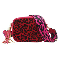 A red and black leopard print crossbody bag with a bright pink and black patterned strap, gold-tone hardware, and a pink tassel charm, shown on a plain white background.