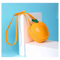 A glossy orange-shaped crossbody bag with a matching wrist strap, styled on white display blocks against a light blue background.