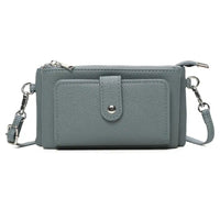 A slate blue pebbled faux leather crossbody wallet with a front pocket, silver snap button, and silver-tone hardware, shown on a white background.