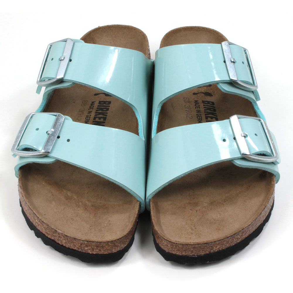 Birkenstock cork and rubber soled, two strap sandals. Two silver buckles on two patent surf green wide straps. Backless design with sculpted insole. Front view.
