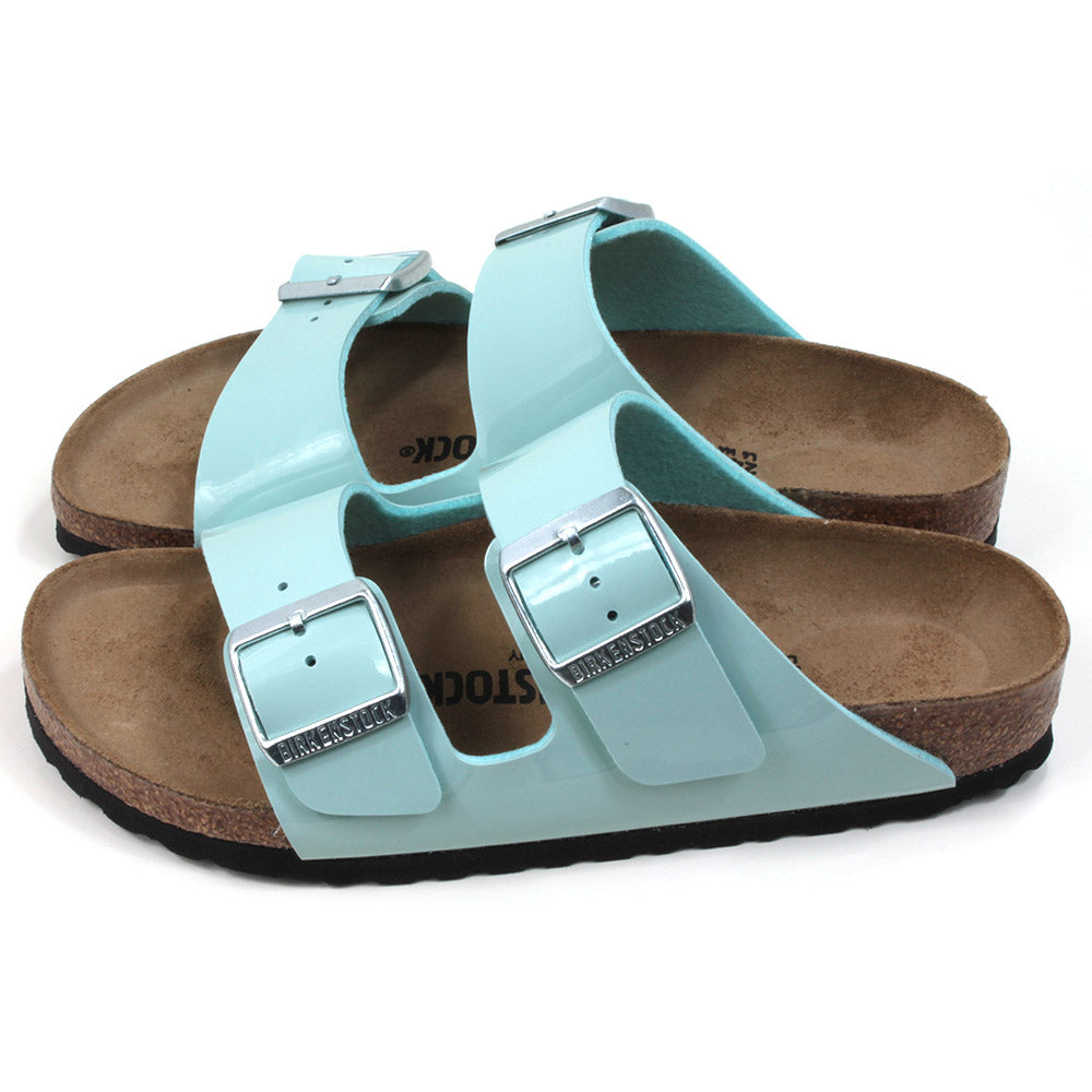 Birkenstock cork and rubber soled, two strap sandals. Two silver buckles on two patent surf green wide straps. Backless design with sculpted insole. Side view.